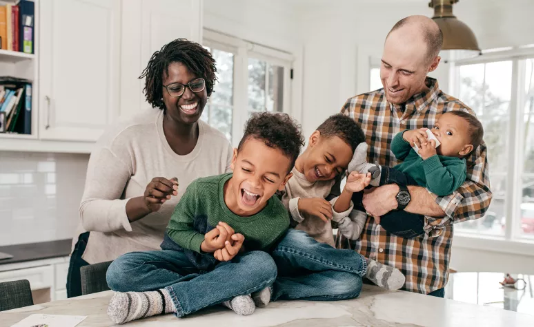 Young parents laugh with their three young boys in the kitchen. Young parents laugh with their three young boys in the kitchen.