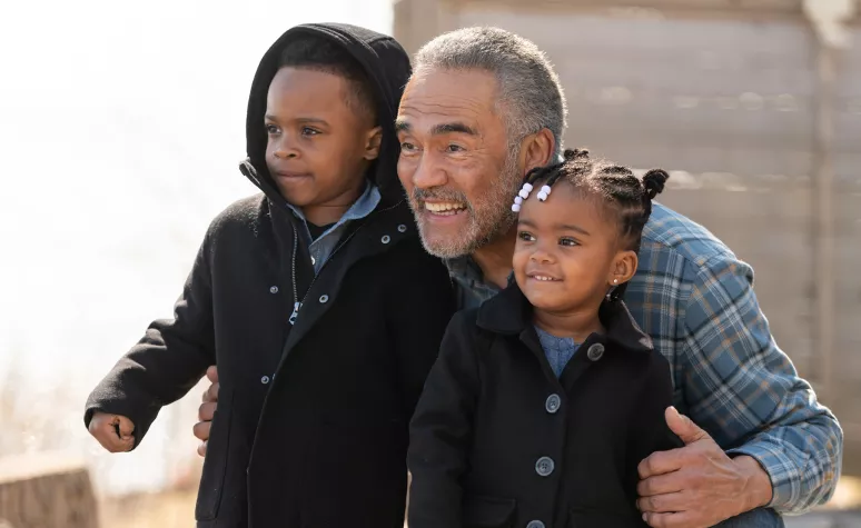 A grandfather and his two young grandchildren pose for a photograph. A grandfather and his two young grandchildren pose for a photograph.