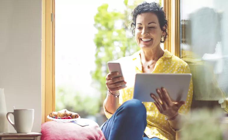 Person sitting in a window, looking at tablet. Person sitting in a window, looking at tablet.