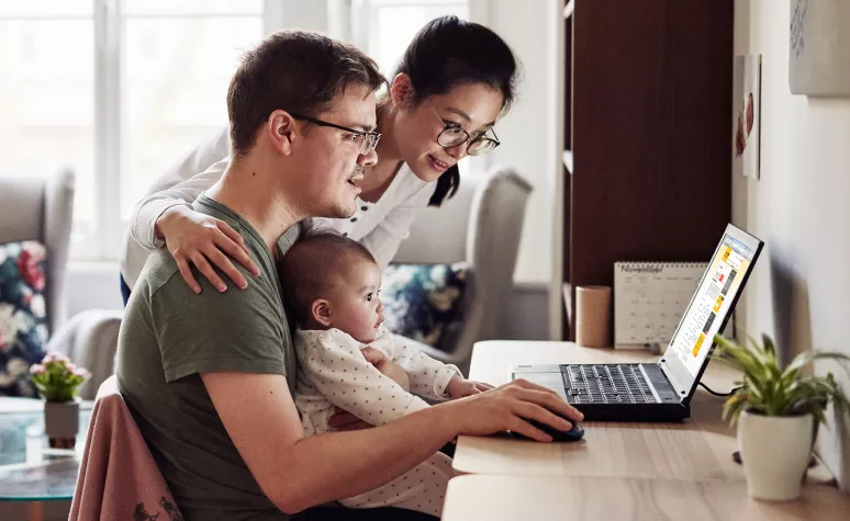 Young parents look up information on their laptop with a small infant on the father's lap. Young parents look up information on their laptop with a small infant on the father's lap.