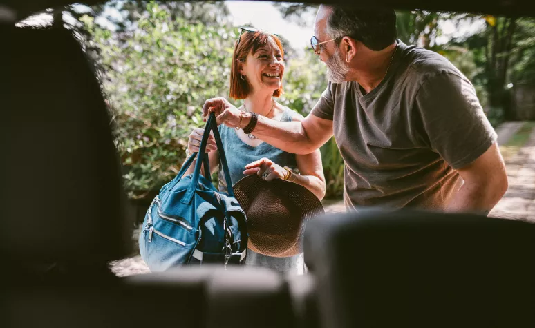 A couple taking their luggage out of a car. A couple taking their luggage out of a car.