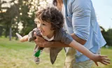  A father and son play together outside.