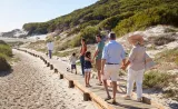 Une famille de trois générations marche ensemble sur la plage.